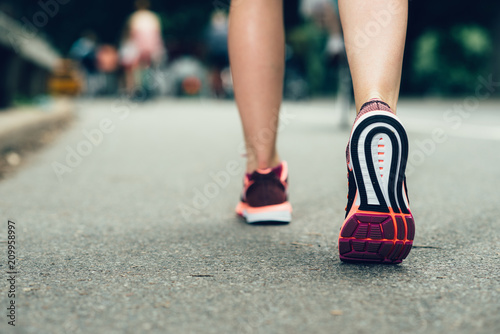 Woman feet closeu-up wearing sneakers during marathon run on asphalt city road