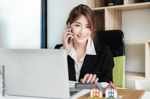 Real estate, Asia business accounting concept, woman using smart phone and laptop computer in office.