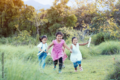 Happy asian children having fun to run and play with toy paper airplane in the meadow together in summer time