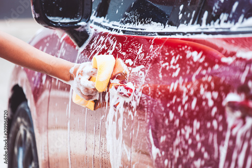 Man washing red car with sponge and soap photo