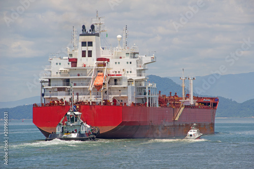 A tanker is assisted by pilot and a tugboat