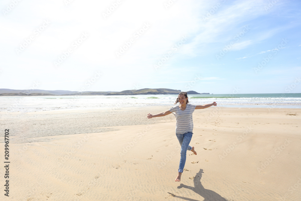 Happy freedom woman running carefree having fun with open arms on beach vacation travel. Summer sunshine holiday destination girl. Life happiness.