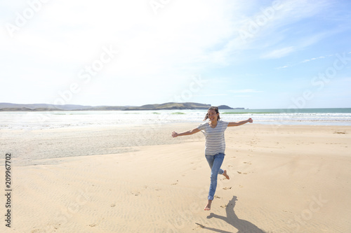 Happy freedom woman running carefree having fun with open arms on beach vacation travel. Summer sunshine holiday destination girl. Life happiness.