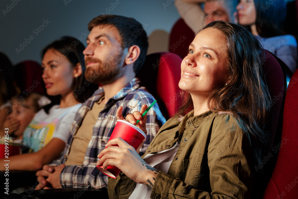 Group of friends sitting in movie theater with popcorn and drinks Group of friends sitting in movie theater with popcorn and drinks