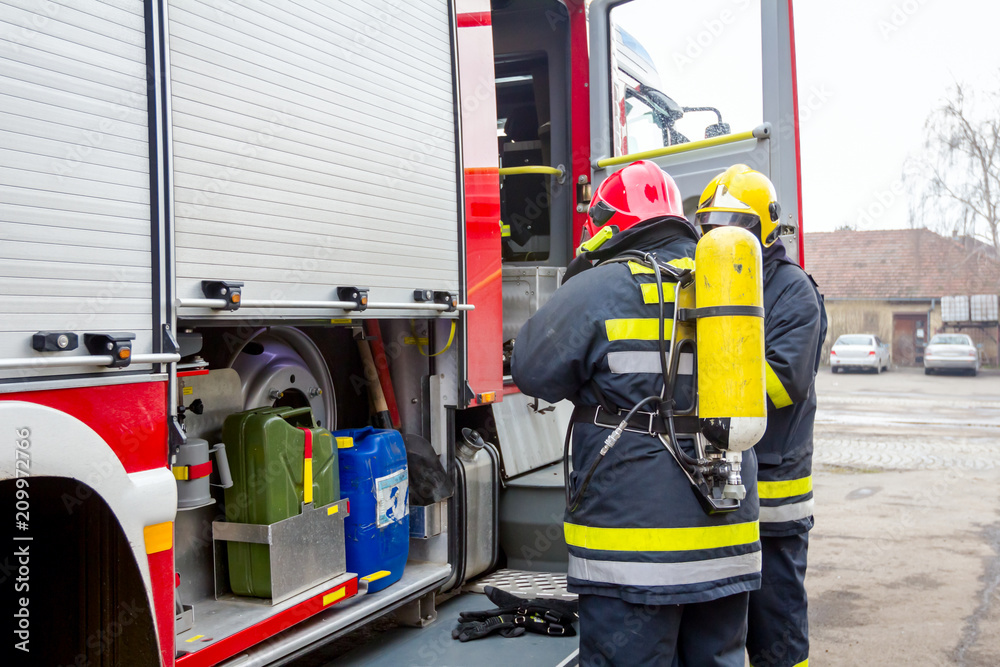 Fireman is helping colleague to manage full safety gear Fireman is helping colleague to manage full safety gear