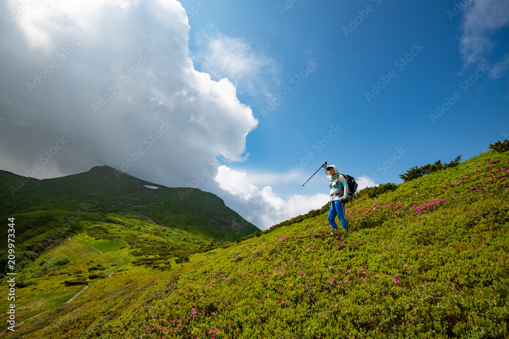 Adventurer female with open arms among flowering rhododendrons Adventurer female with open arms among flowering rhododendrons