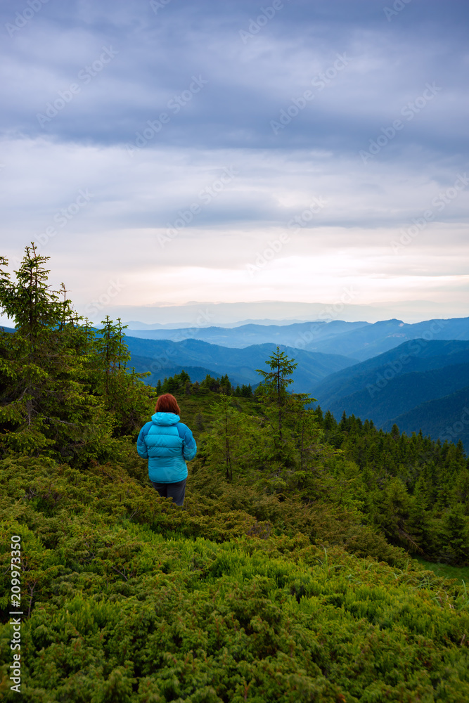 Fototapeta premium Adventurer female is standing on the mountain slope