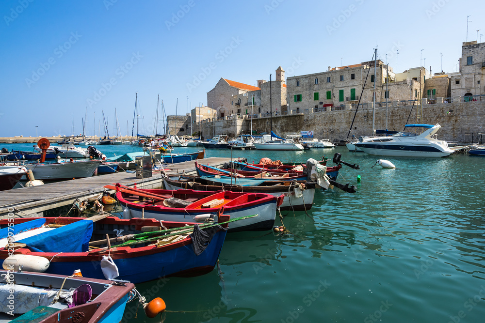 Colorful boats at Giovinazzo harbour with the Cathedral on the background, Apulia, Italy