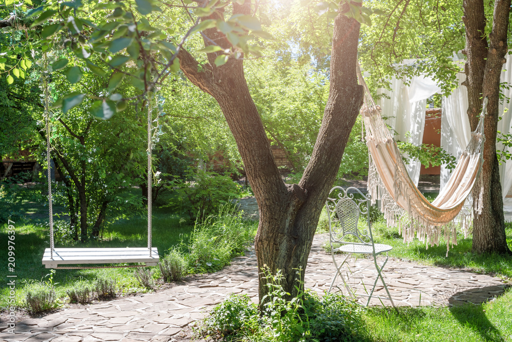 Wooden swing on ropes and hammock under the big tree in the garden. Stock  Photo | Adobe Stock