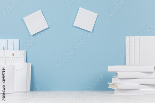 School template -  white books  stationery  blank stickers on white desk and soft blue background. Back to school background with copy space.