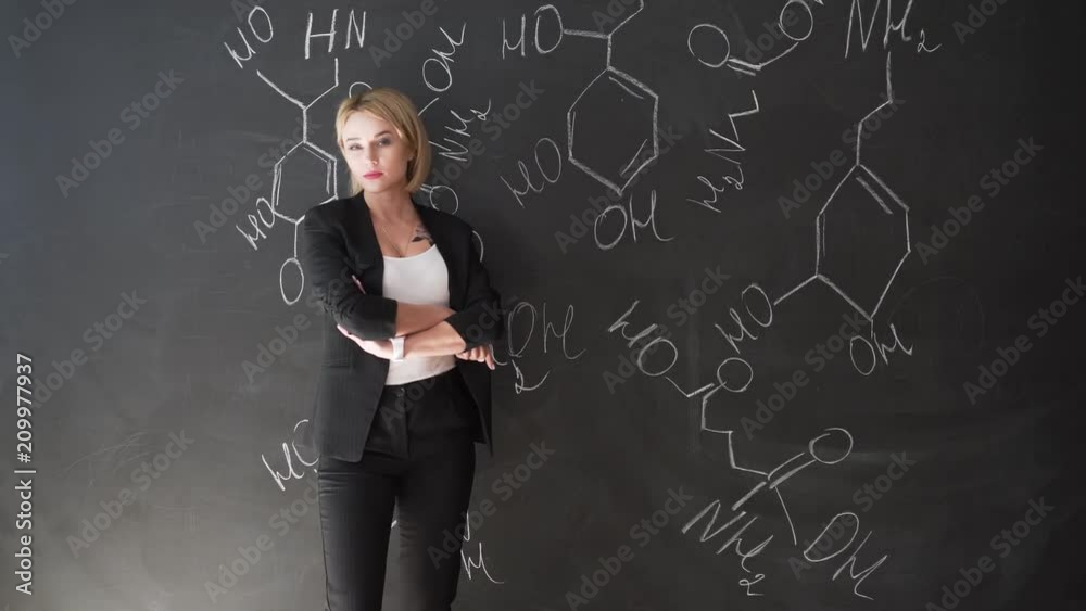 Teacher writing formulas on the chalk Board and explains the students the formula. Teacher writing formulas on the chalk Board and explains the students the formula.