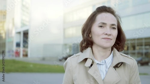 A woman walks with a suitcase to the airport building. A business lady walks with a suitcase on wheels to the parking lot. Travel concept. photo