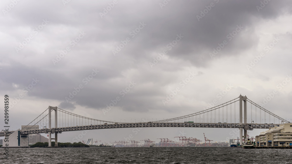 Fototapeta premium Panoramic view of the Rainbow Bridge in Tokyo, Japan, on a rainy day with cloudy sky