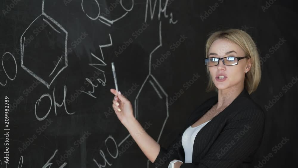 Teacher writing formulas on the chalk Board and explains the students the formula. Teacher writing formulas on the chalk Board and explains the students the formula.