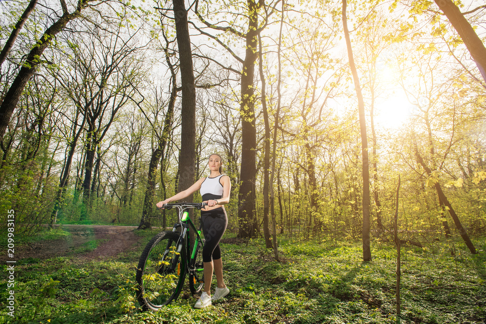 Active life. Sport girl trailing on a bike enjoys the view of sunset over an forest. Heathy lifestyle concept. Text placement