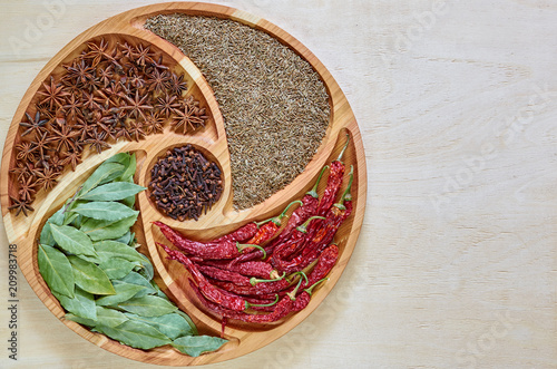 Mix of asian spices on the wooden plate: star anise, bay leaves, paprika, dried cloves and cumin close up. Spices texture background with copy space. Ingredients for tasty food and cuisine. Top view