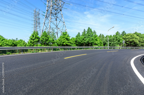 Curved asphalt highway and green forest on a sunny day