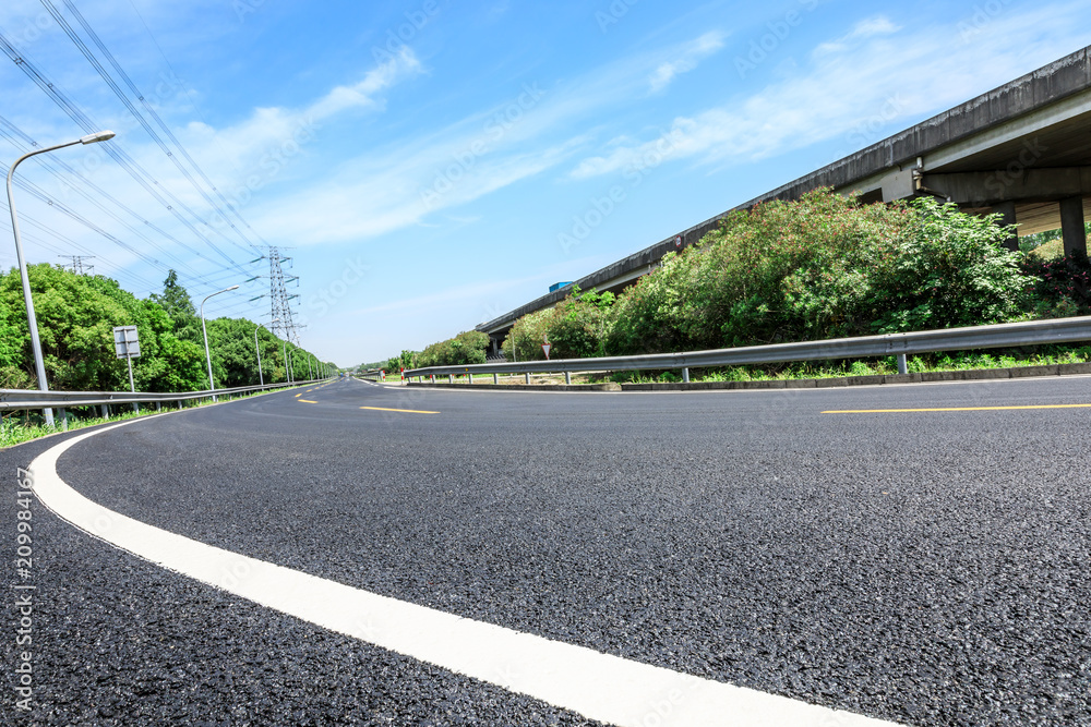 Curved asphalt highway and green forest on a sunny day