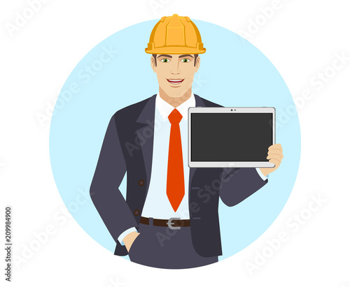 Businessman in construction helmet with hand in pocket showing blank digital tablet PC