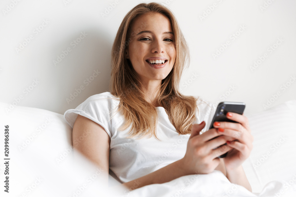 Cheerful pretty young woman lies in bed. Cheerful pretty young woman lies in bed.