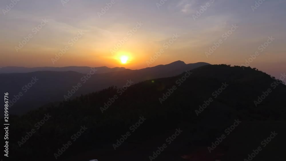 Panoramic view of green hilltop forest and mountain with distant sunset Panoramic view of green hilltop forest and mountain with distant sunset