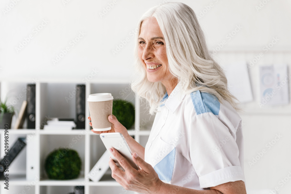 Mature happy woman drinking coffee using mobile phone. Mature happy woman drinking coffee using mobile phone.