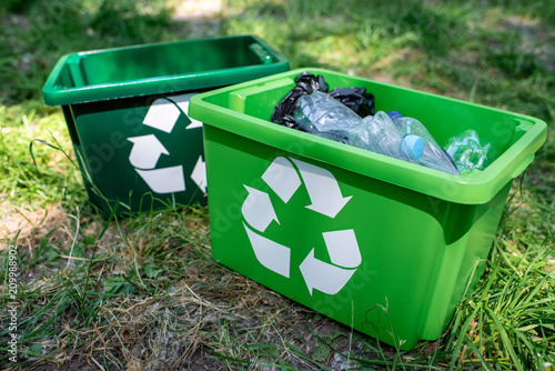 green recycling boxes with plastic trash standing on lawn