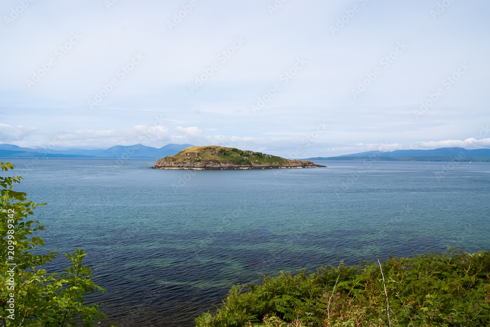 Isle in sea in Oban, United Kingdom. Archipelago on idyllic sky. Summer vacation on island. Adventure and discovery. Travelling and wanderlust