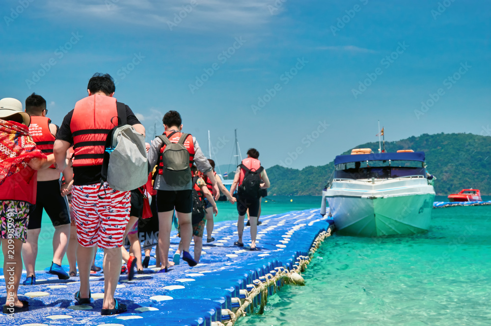 Obraz premium Tourists go by the boat at the pier plastic. Travelers in life jackets sit on board a sea speedboat. Concept activities at the sea