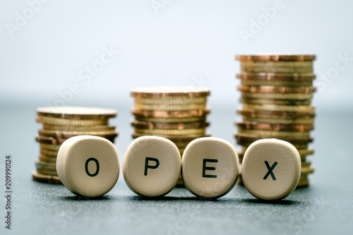 OPEX letter block and stack coins, business concept. OPEX stands for Operational Expenditure. photo