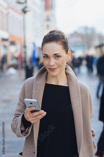 Street portrait of young smiling woman with phone