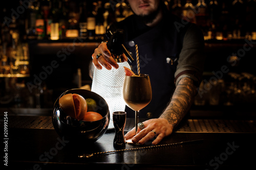 Bartender adding cocktail from the syphon to the copper cup