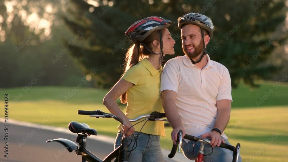 Young couple with bicycles on road. Beautiful young couple standing with bicycles on road, looking at each other and smiling. Romatic vacation on bicycles. Young couple with bicycles on road. Beautiful young couple standing with bicycles on road, looking at each other and smiling. Romatic vacation on bicycles.