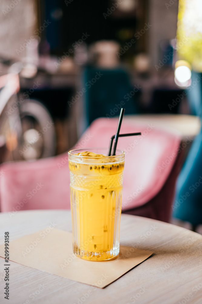 Beautiful glass of yellow passionfruit lemonade on the wooden table. Flatlay style, spotted on the city cafe. Beautiful glass of yellow passionfruit lemonade on the wooden table. Flatlay style, spotted on the city cafe.