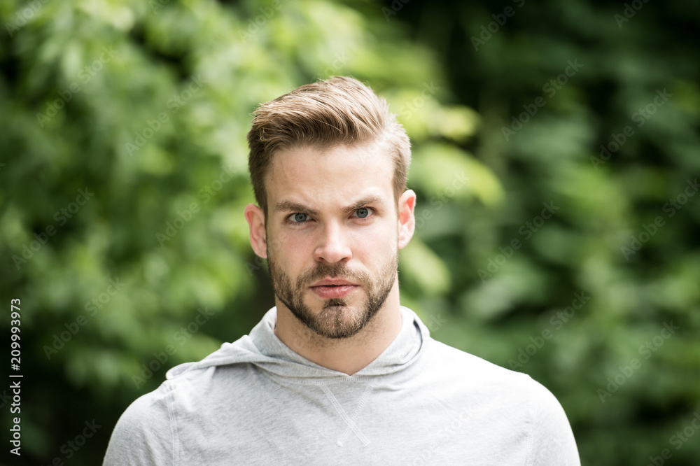 Macho with beard on unshaven face on natural landscape. Bearded man with serious look on fresh air. Taking a minute break. Casual in style. Sporty handsome Macho with beard on unshaven face on natural landscape. Bearded man with serious look on fresh air. Taking a minute break. Casual in style. Sporty handsome