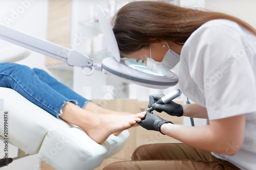 Podiatrist doctor in white making polish procedure for foot.
