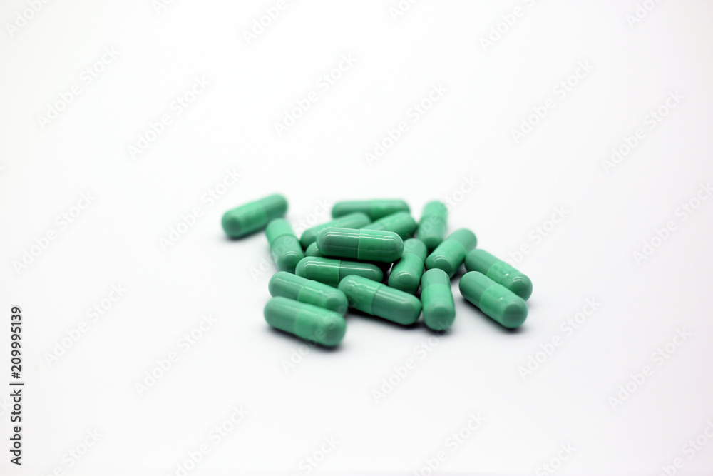 Green capsules pill isolated in white background. Closeup green drug for health or pharmaceutical concept. Green capsules pill isolated in white background. Closeup green drug for health or pharmaceutical concept.