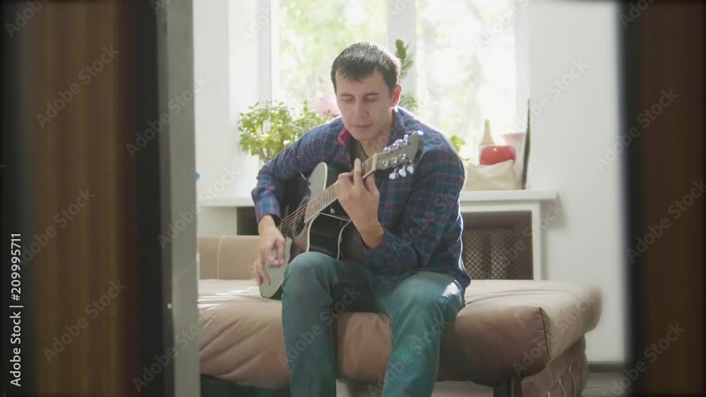man playing music by wooden acoustic guitar. Man Playing Acoustic Guitar Close Up slow motion video. in the room sits on the couch. man lifestyle and guitar concept man playing music by wooden acoustic guitar. Man Playing Acoustic Guitar Close Up slow motion video. in the room sits on the couch. man lifestyle and guitar concept