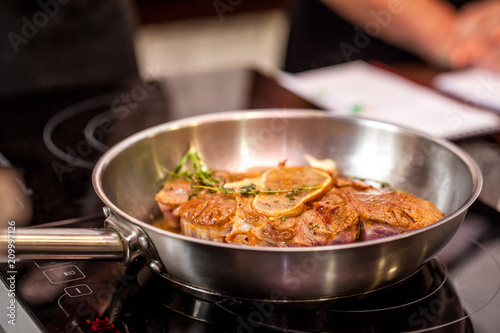 oncept of the correct cooking of meat. The chef prepares, fries a steak of mutton, pork or veal in a frying pan on an induction cooker, with the addition of spices, marinade and wine. Selective focus