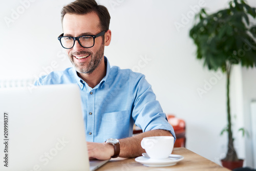 Handsome man at cafeteria, cafe working on laptop