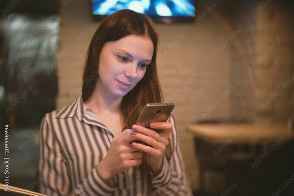 Woman is browsing internet in her mobile phone and looking at camera and smiling. Woman is browsing internet in her mobile phone and looking at camera and smiling.