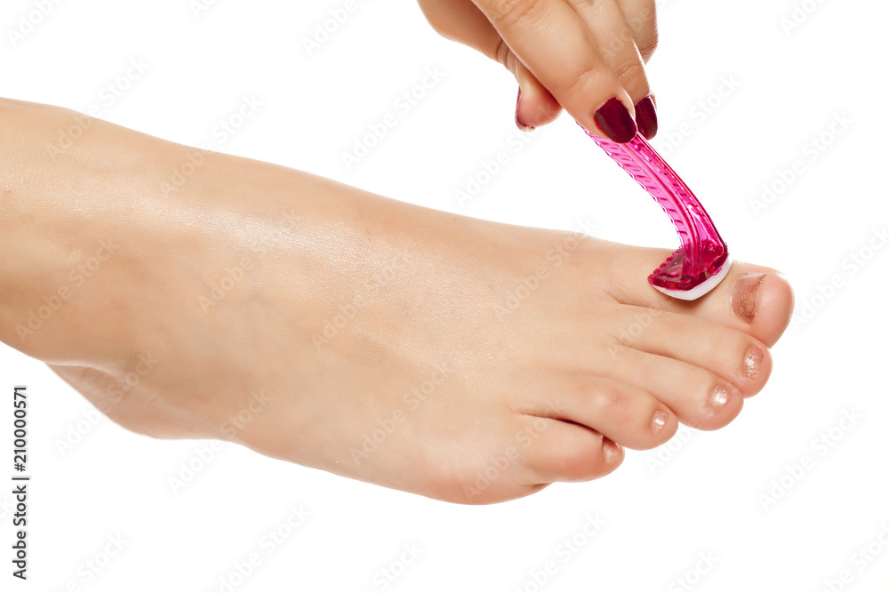 young woman shave the hairs on her toe with razor on white background