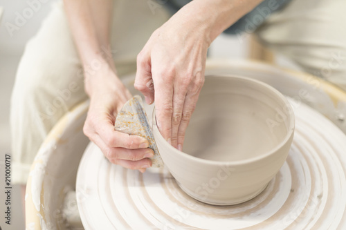 Woman hands makes clay pot on the pottery wheel photo
