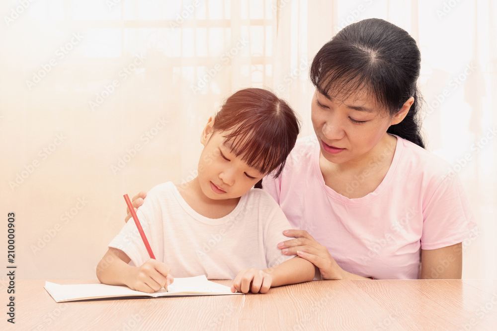 Asian Chinese mother teaching daughter doing homework Asian Chinese mother teaching daughter doing homework