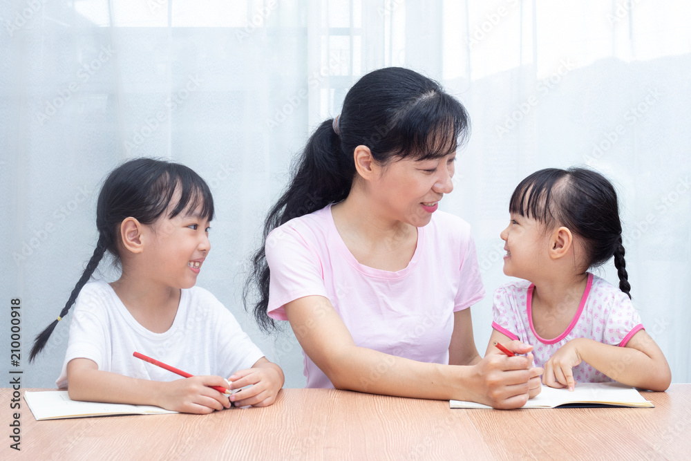 Asian Chinese mother teaching daughters doing homework Asian Chinese mother teaching daughters doing homework