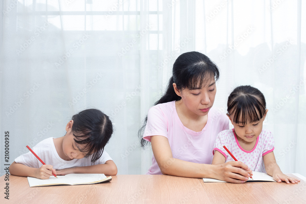 Asian Chinese mother teaching daughters doing homework Asian Chinese mother teaching daughters doing homework