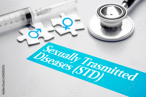 Sexually Transmitted Diseases -  STD, medical concept. Puzzle with male and female symbol, syringe and stethoscope on grey background. Selective focus image.