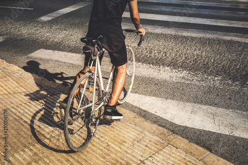 Man crossing a crosswalk with his old road bike, wearing casual clothes. © daviles