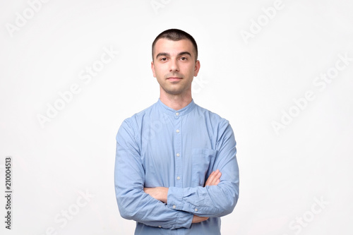 Portrait of happy fashionable handsome man in blue shirt crossing hands and look at camera.