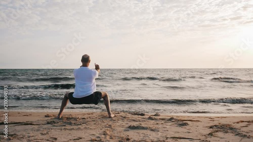 Man standing in horse stance Ma Bu while morning training WuShu on sea shore